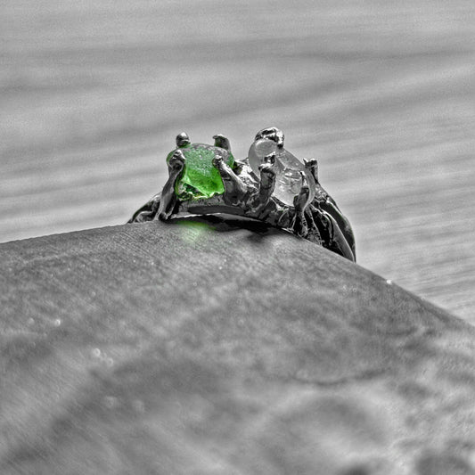 Close-up of a ring with a green and a white sea glass on a gray background
