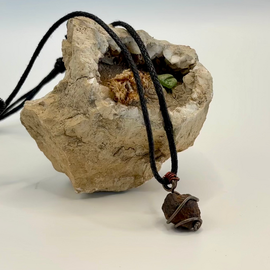 Close-up of red and copper wire wrapped iron ore pendant