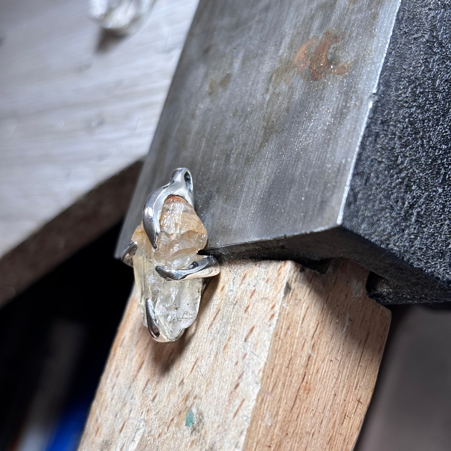 Close-up of a crystal on a wooden surface with a metal tool. handmade silver jewelry