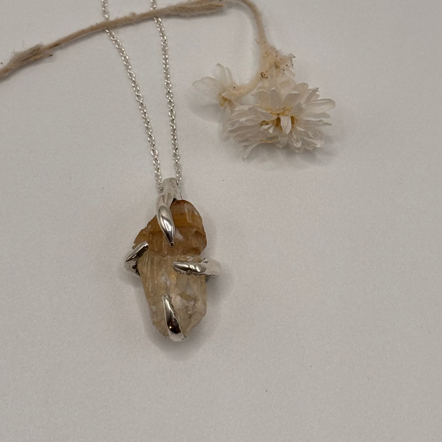 silver Necklace with a raw calcite stone pendant on a light gray background