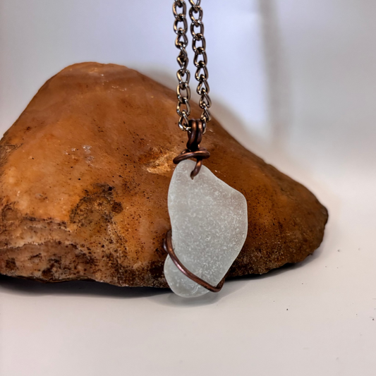 Close-up of copper wire wrapped white sea glass pendant
