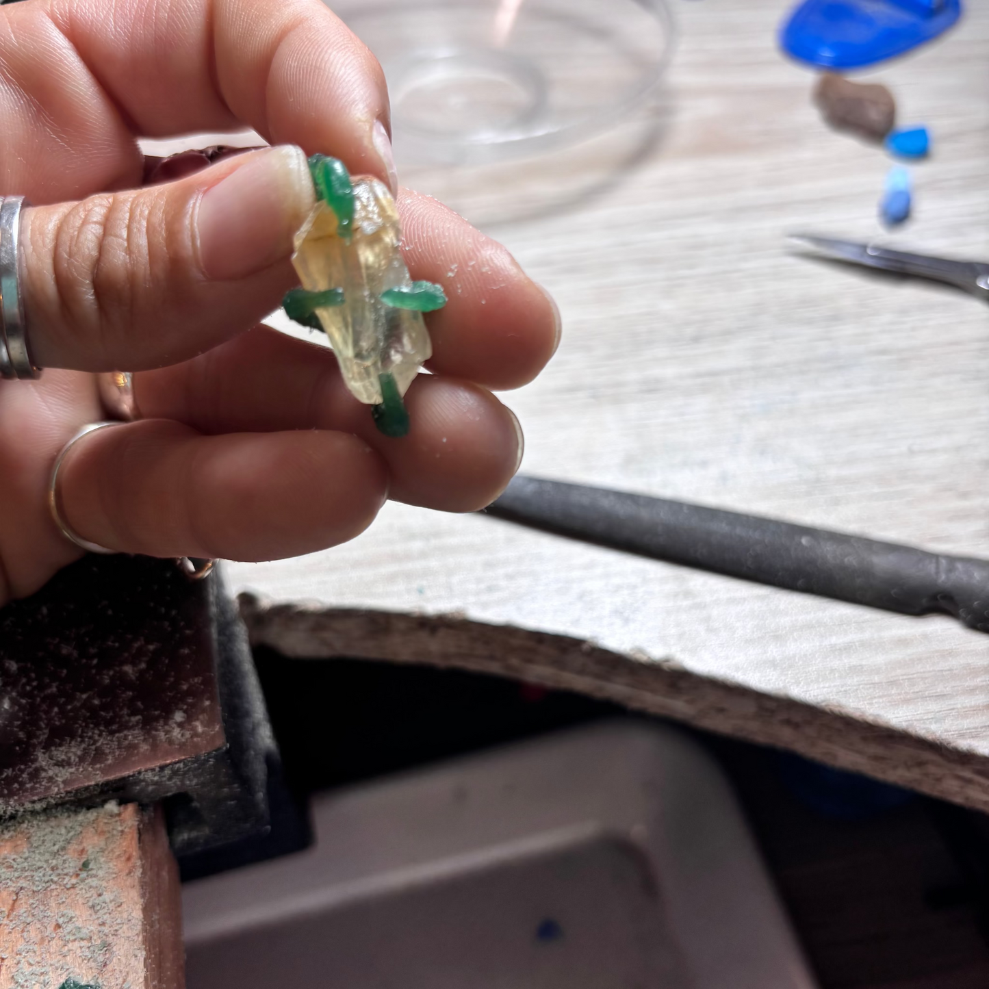 Hand holding a small calcite with green wax using the lost wax technique
