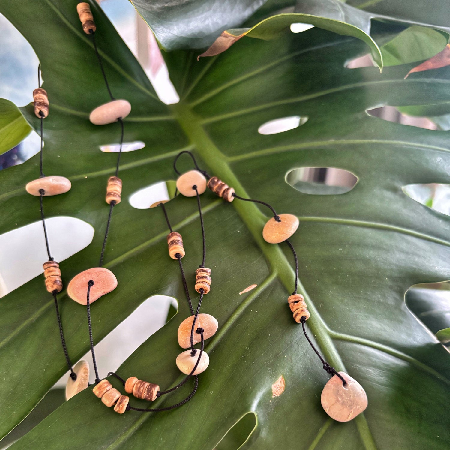 Necklace with pink and brown beads on a green leaf