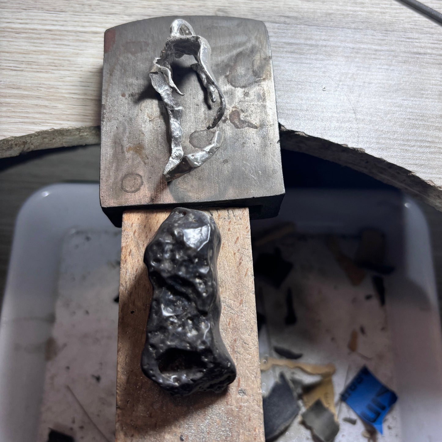 Black stone with a hole and the silver setting that will hold it in a pendant