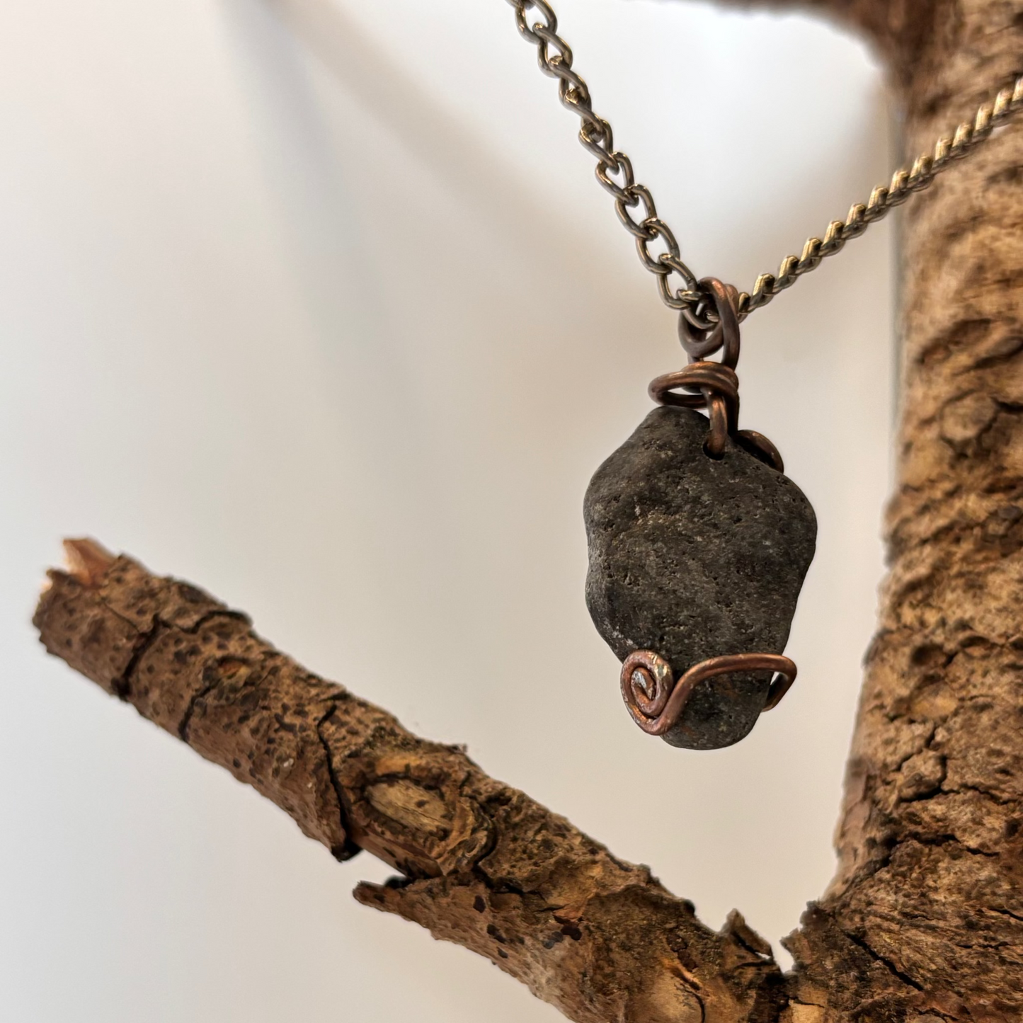 Raw black beach stone wrapped in copper wire on black aluminum chain