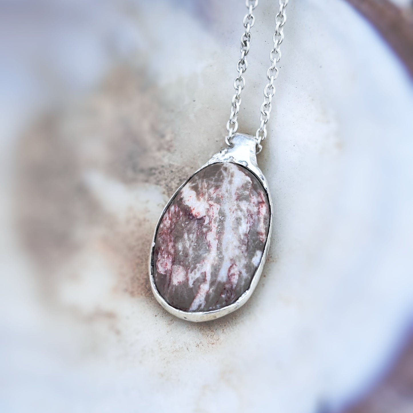 Close-up of silver pendant showing hand-sculpted detail