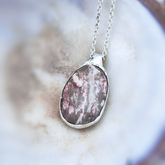 Close-up of silver pendant showing hand-sculpted detail