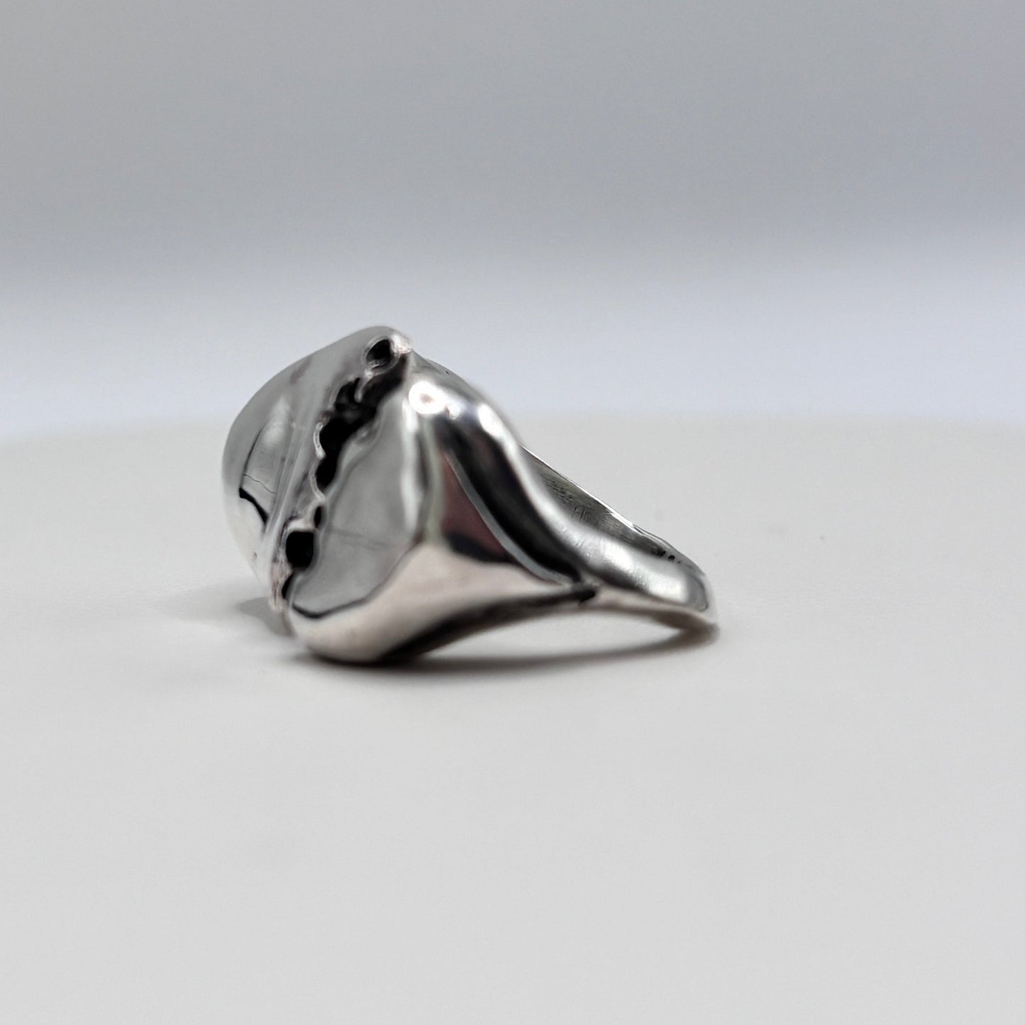The split Silver ring with a unique design with white sea glass in the side on a white background.