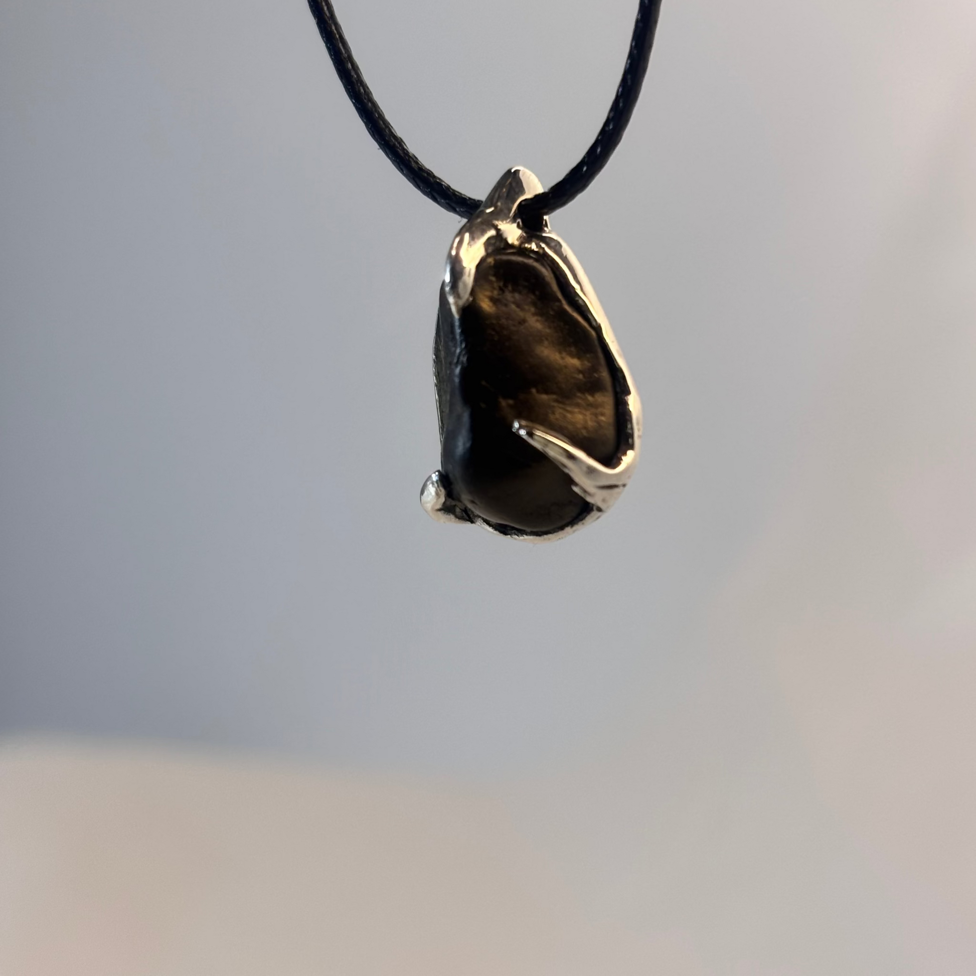 Black beach stone held by three silver prongs, lost wax cast