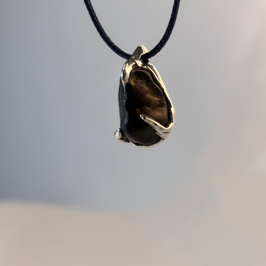 Black beach stone held by three silver prongs, lost wax cast