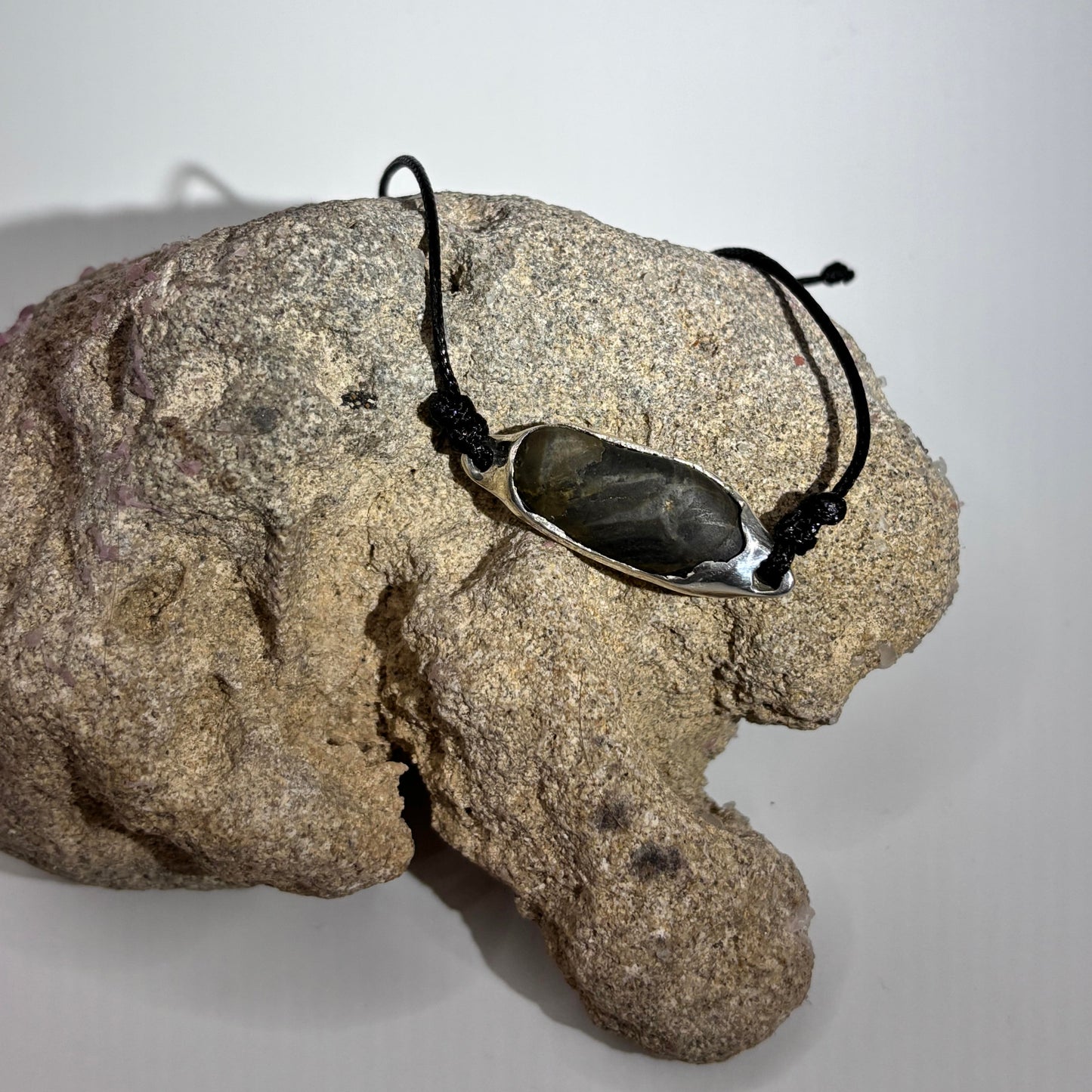bracelet in silver with a black stone on a rock against a white background