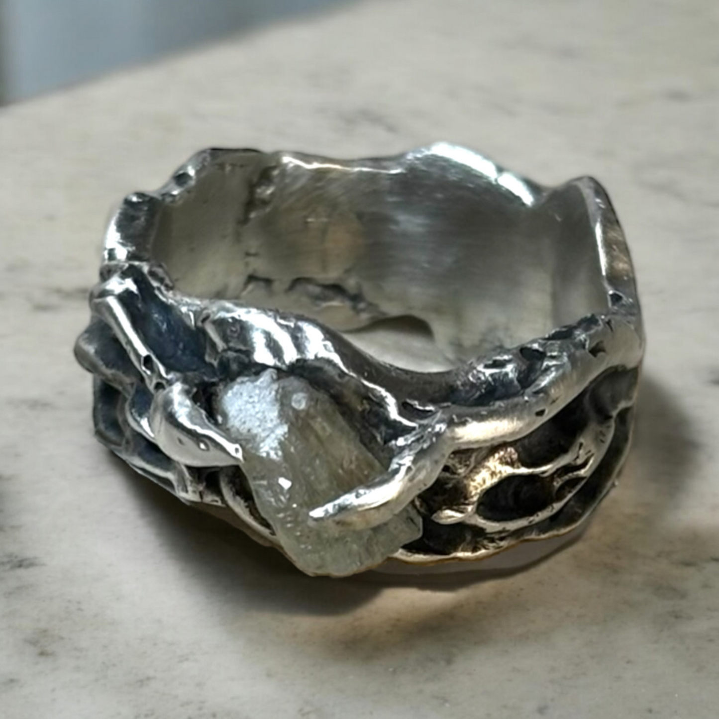 Silver ring holding a raw calcite stone in two bold claws