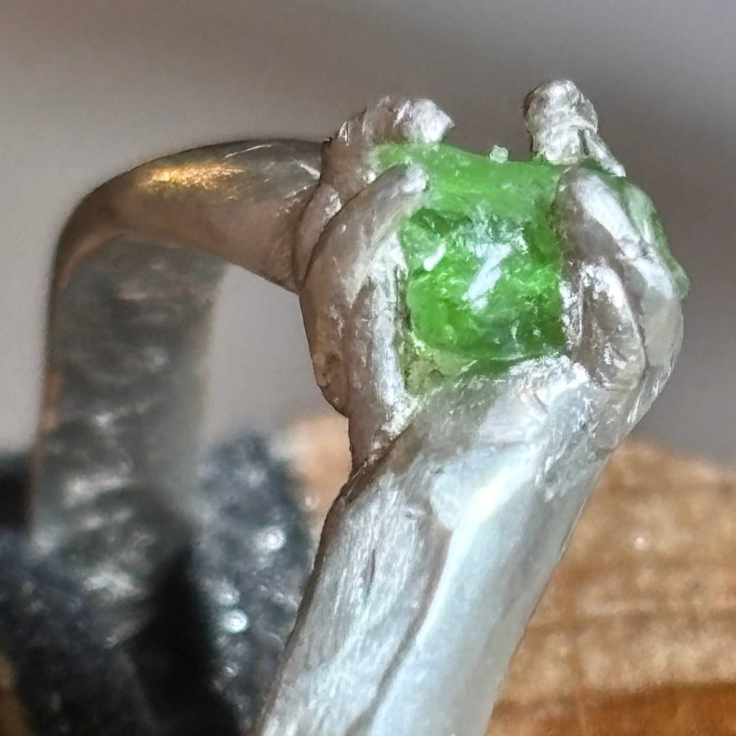 A close-up of a handmade silver ring with a green sea glass