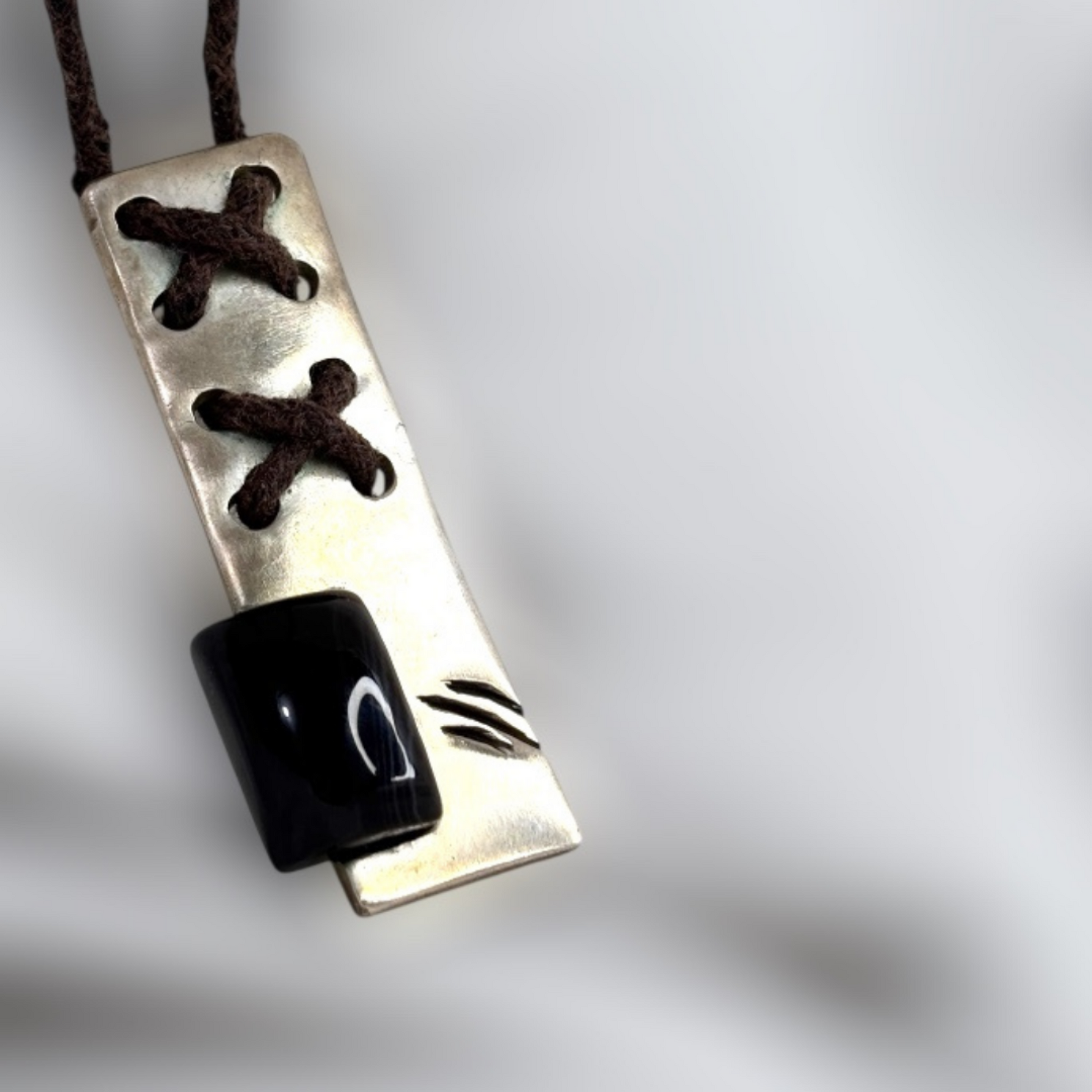 Silver pendant with corset-style lace detailing and black onyx