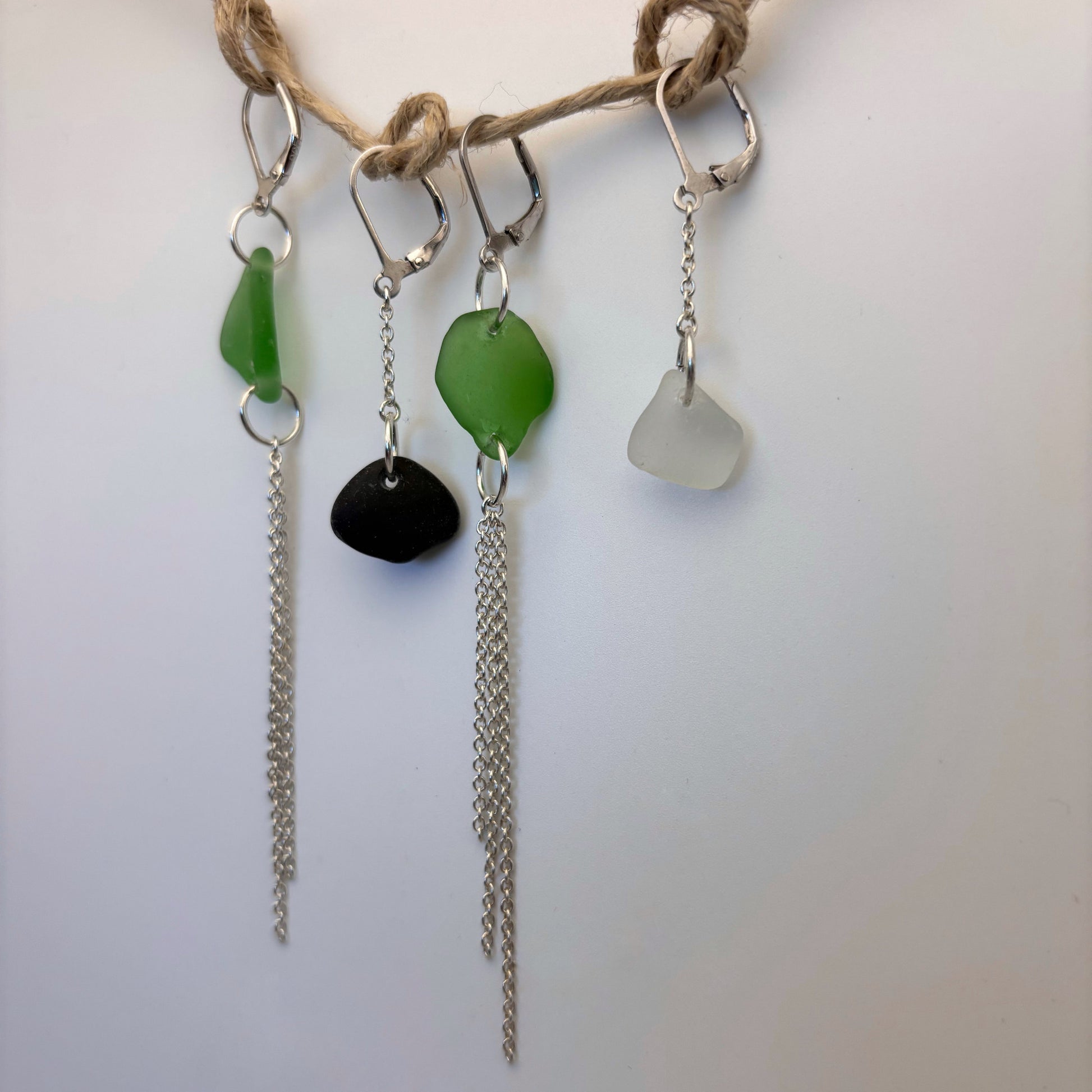 Handcrafted earrings featuring green sea glass and flowing silver wire drops.