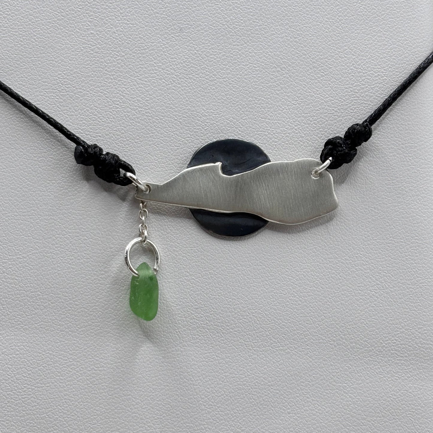 Silver pendant with a green stone on a white background