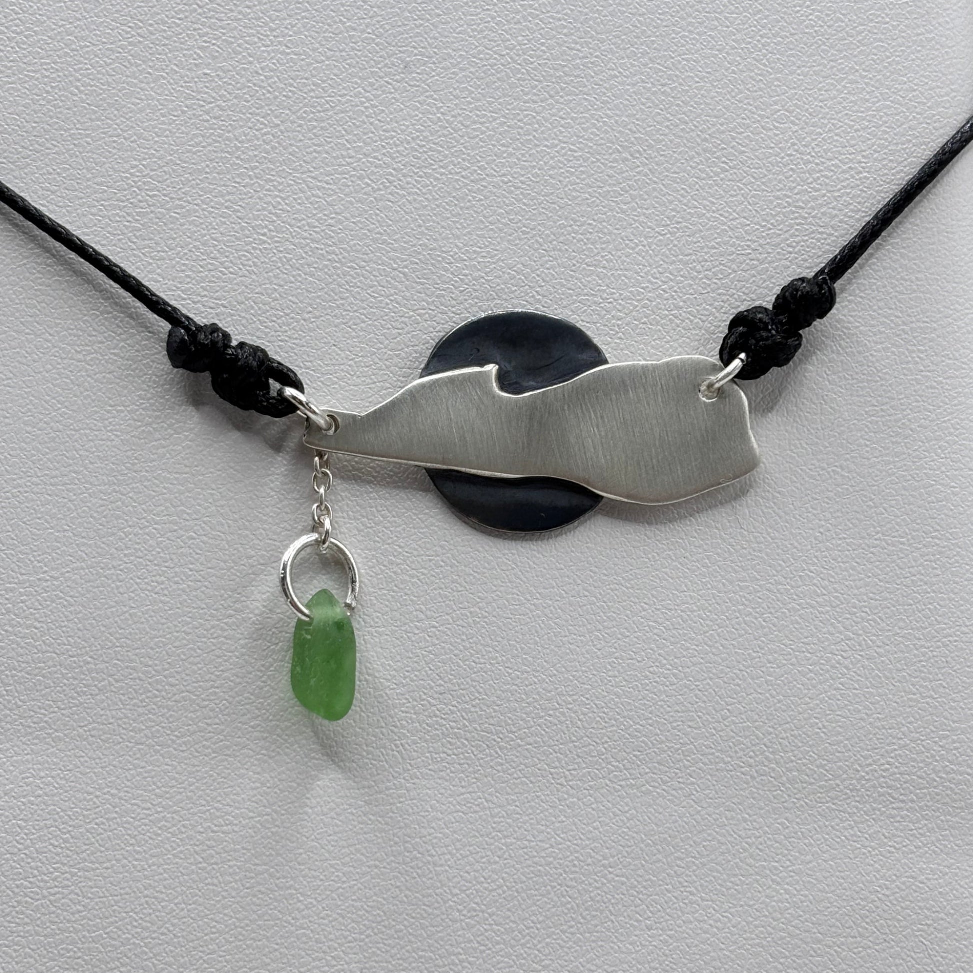 Silver pendant with a green stone on a white background