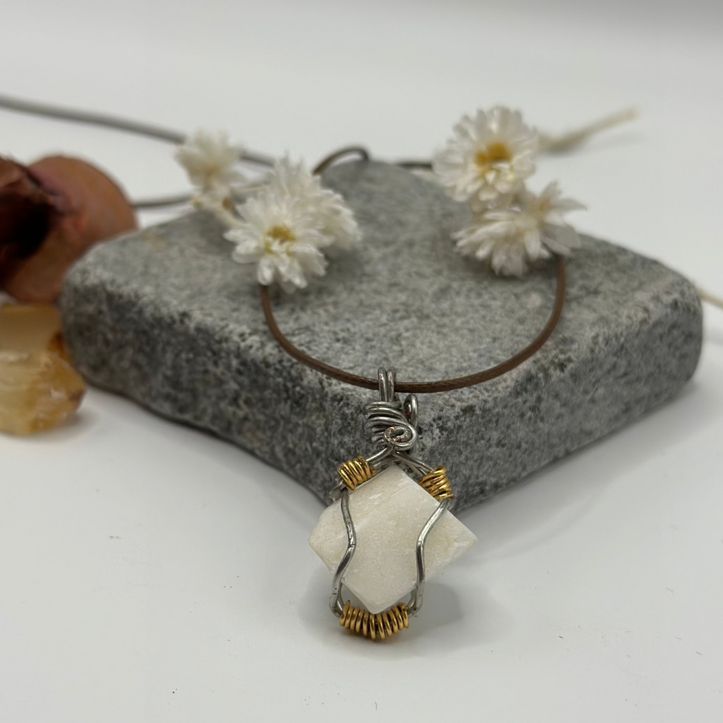 Necklace with a pendant on a stone surface with flowers