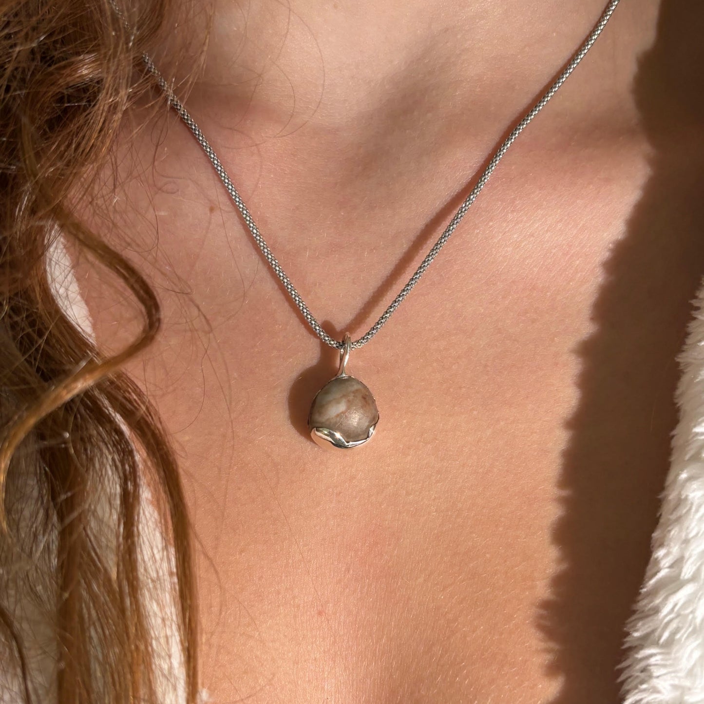 Necklace with a pendant worn by a person, close-up view.