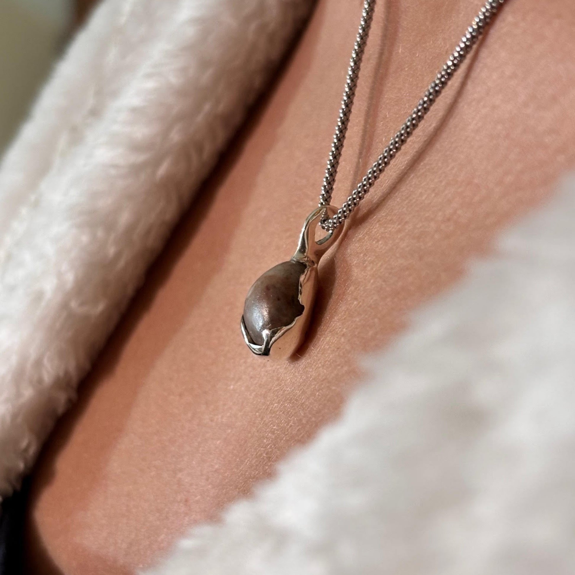 Necklace with a pendant worn by a person in a white garment