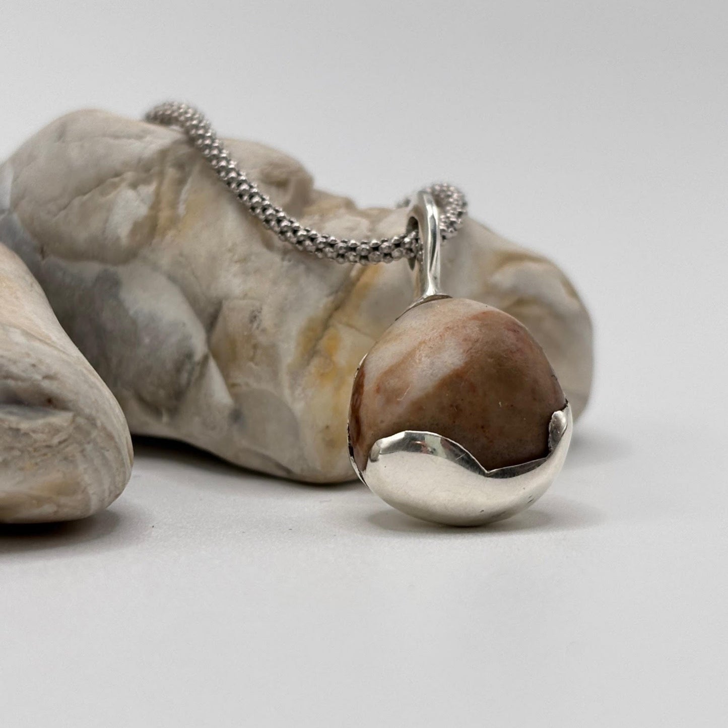 Silver necklace with a pendant on a rock