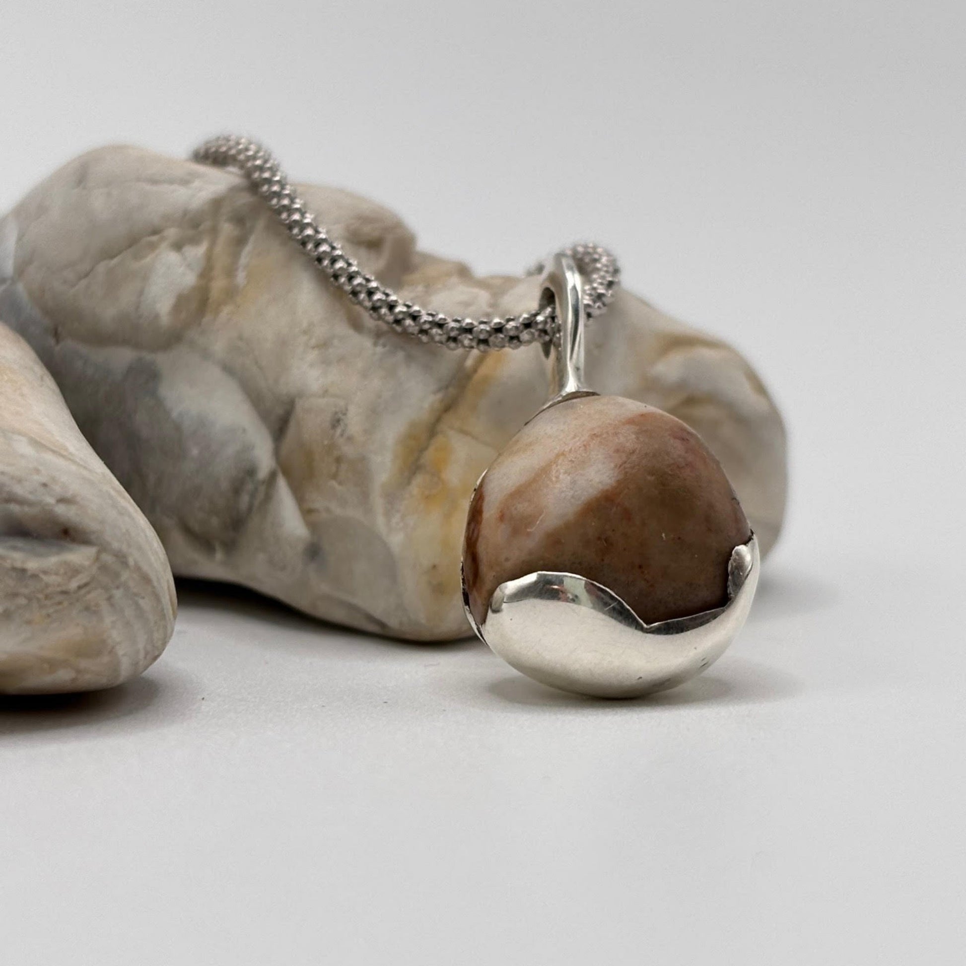 Silver necklace with a pendant on a rock