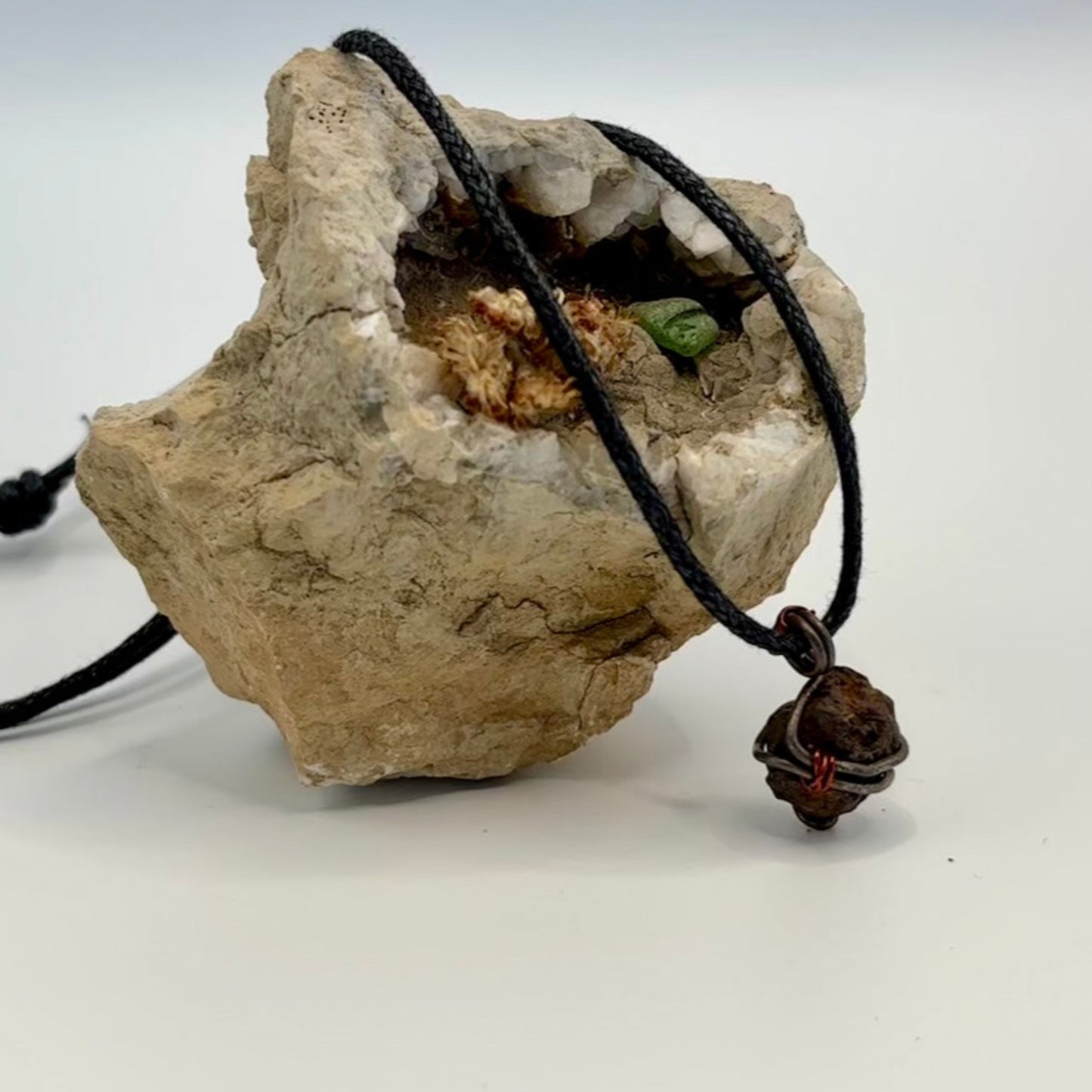 Necklace with a pendant on a rock against a white background