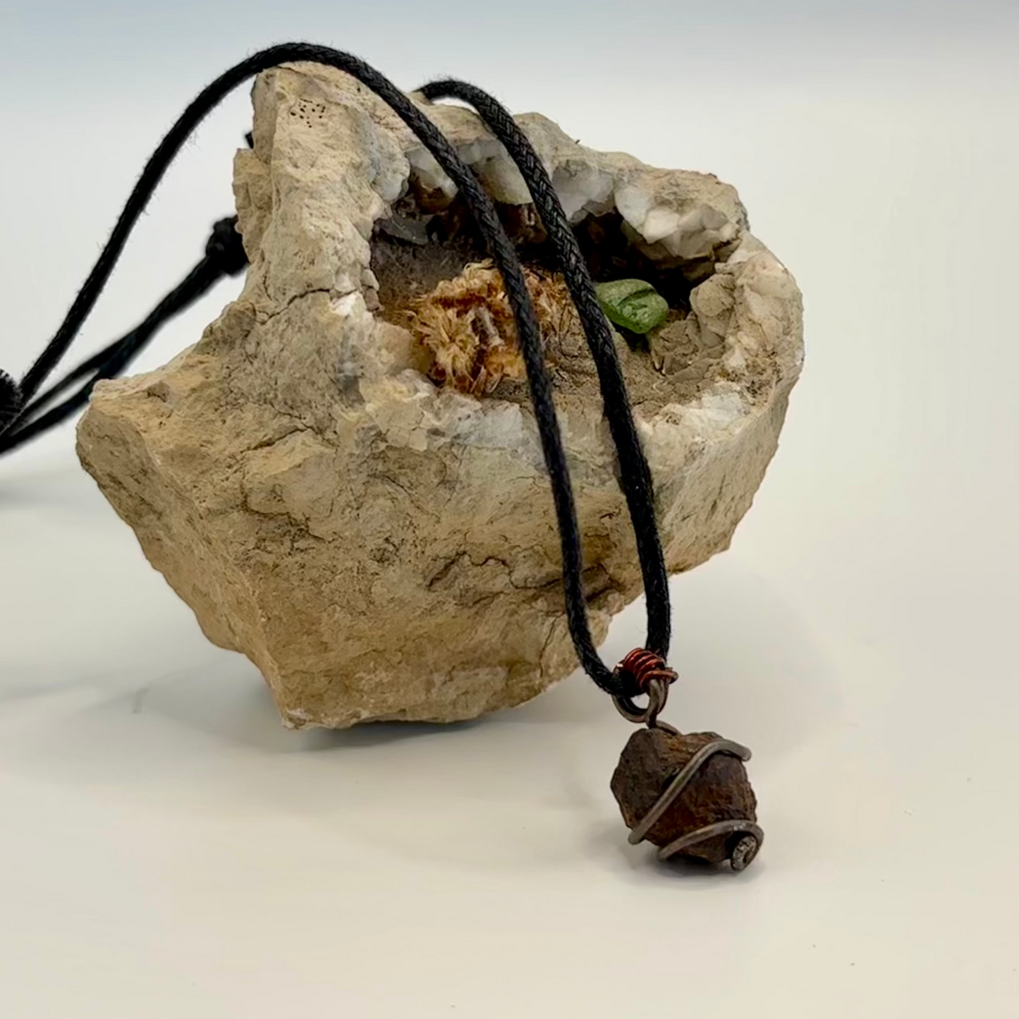 Close-up of red and copper wire wrapped iron ore pendant