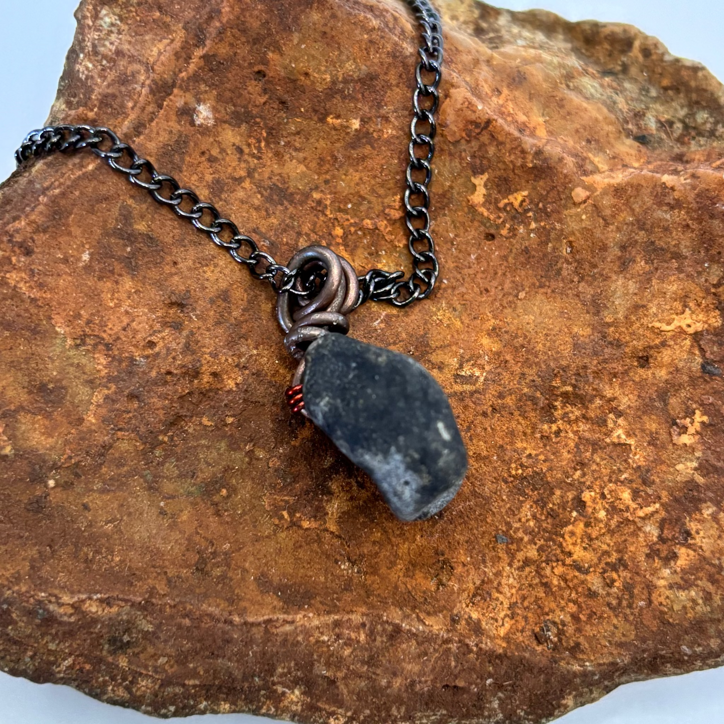 Copper wire pattern detail on black beach stone pendant