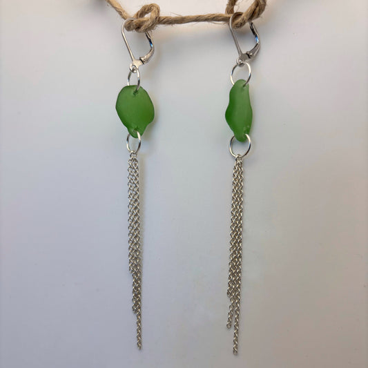 Handcrafted earrings featuring green sea glass and flowing silver wire drops.