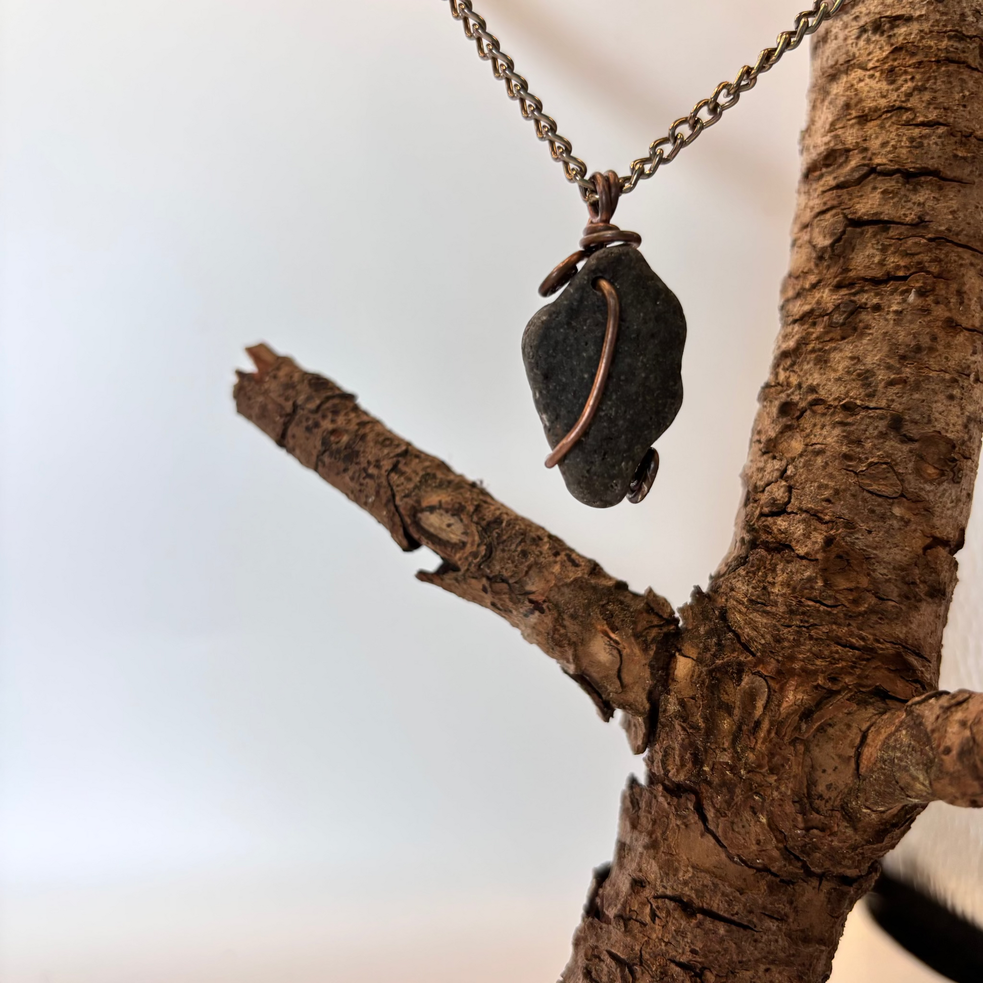 Close-up of copper wire pattern on black stone necklace pendant