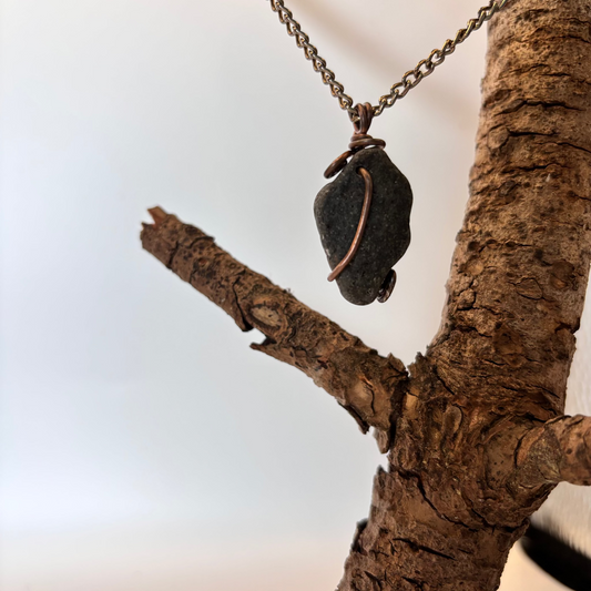 Close-up of copper wire pattern on black stone necklace pendant