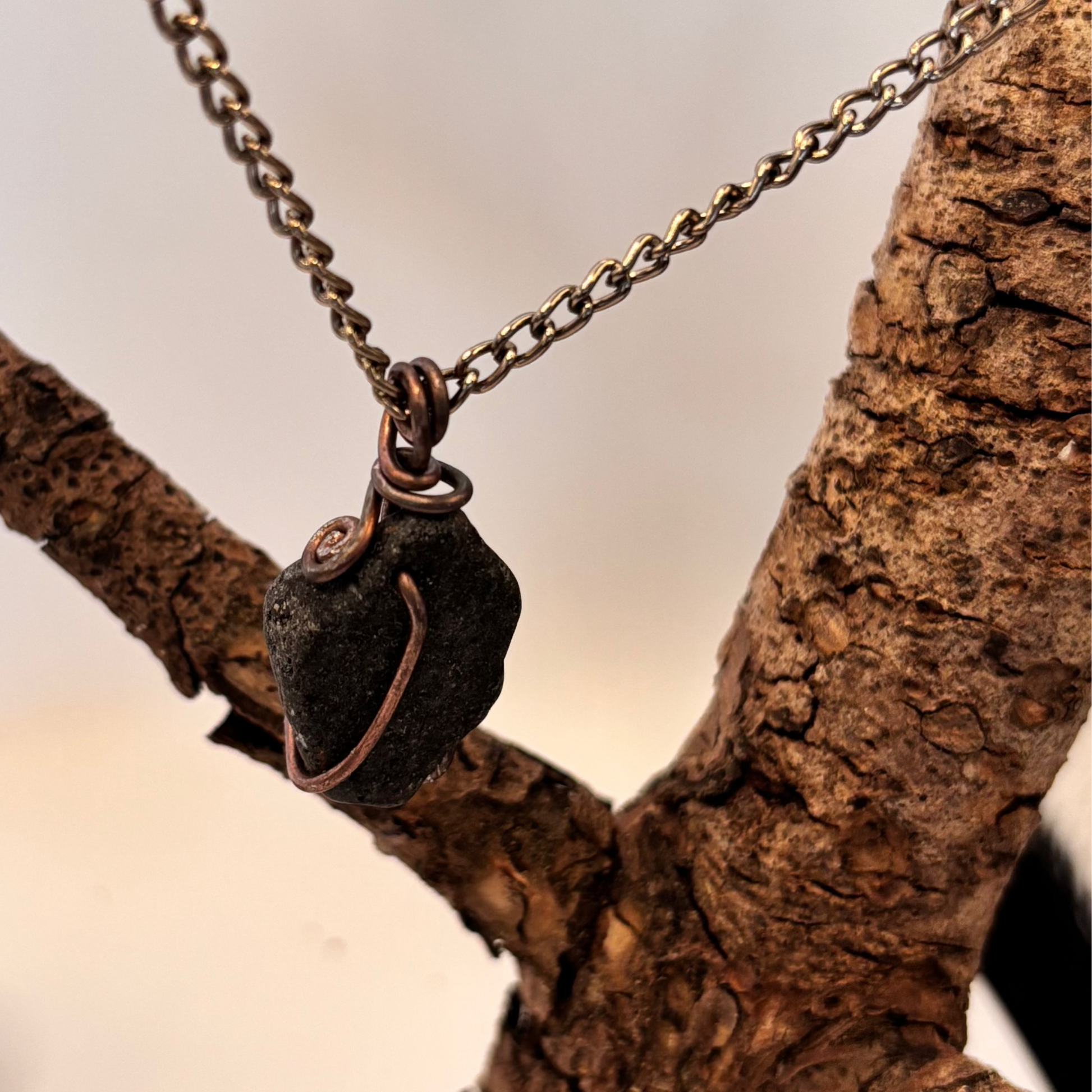 Black stone pendant detail showing natural wire wrap lines