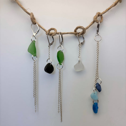 Jewelry with colorful stones and chains hanging from a rope on a white background. earrings silver