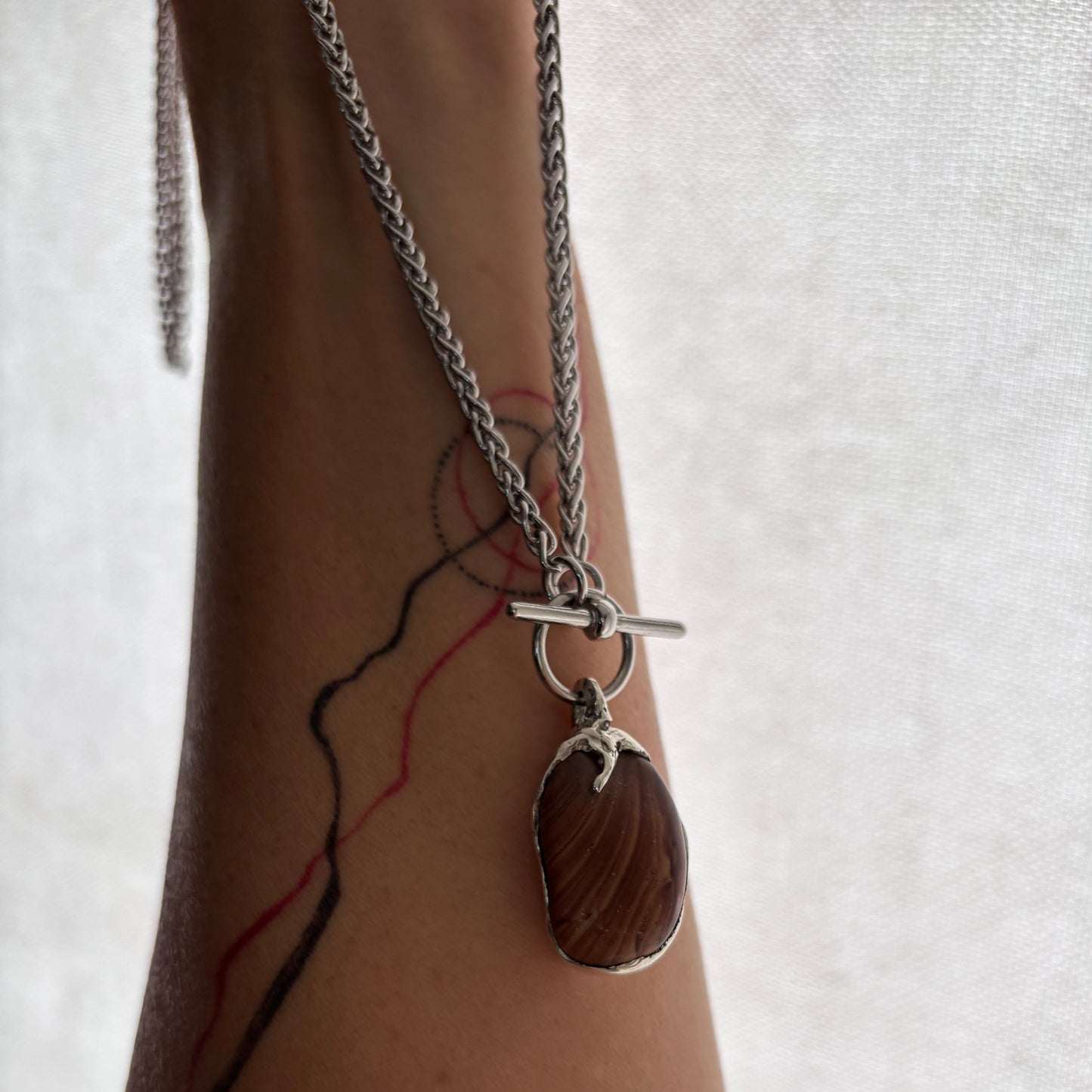 A striped stone, sea-worn and one of one, set in sterling silver with a sculpted claw. Handmade in Lebanon.