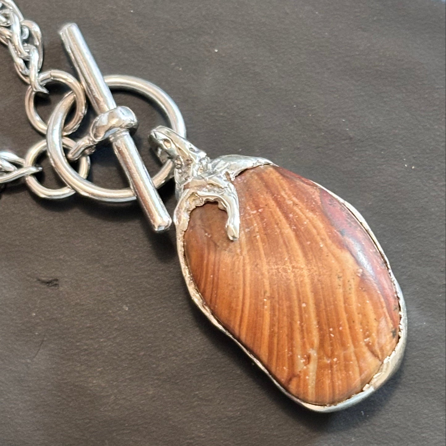 A one-of-one oval striped stone set in a sterling silver bezel with sculpted claw, on a chain with toggle clasp. Handmade in Lebanon.