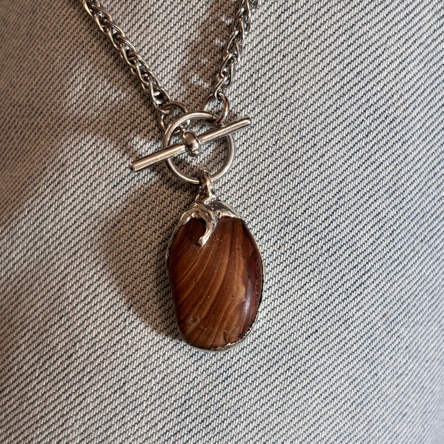 A striped stone, sea-worn and one of one, set in sterling silver with a sculpted claw. Handmade in Lebanon.