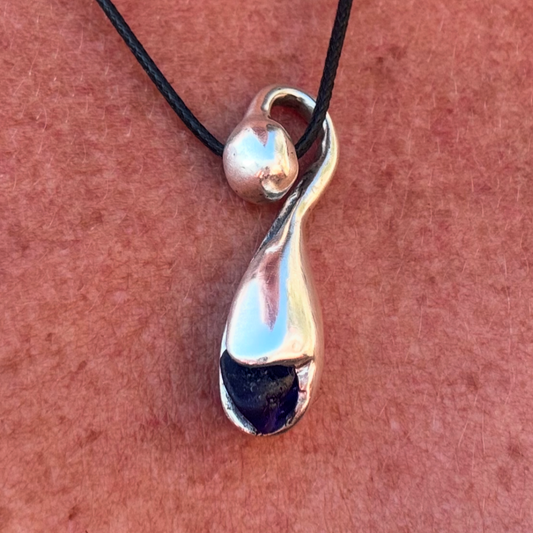 Close-up of Rebirth & Bloom pendant showing curved silver detail
