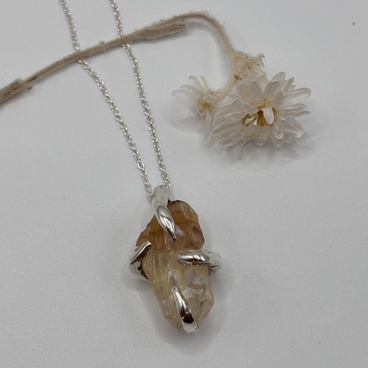 Silver Necklace with a raw calcite pendant featuring a natural stone on a light gray background. handmade jewelry