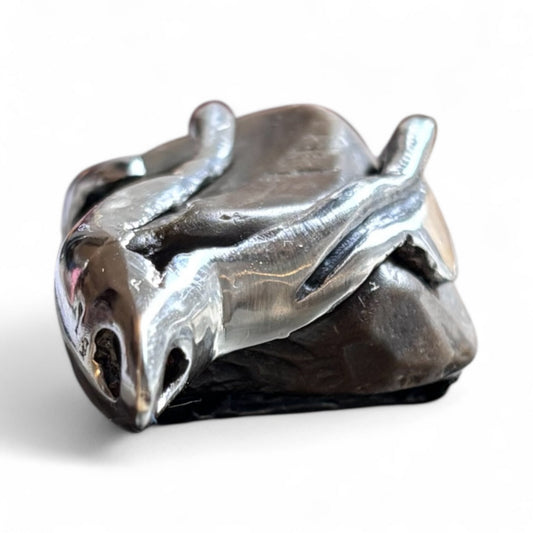 Close-up of a handmade pendant with a raw beach stone encased in an organic silver design.