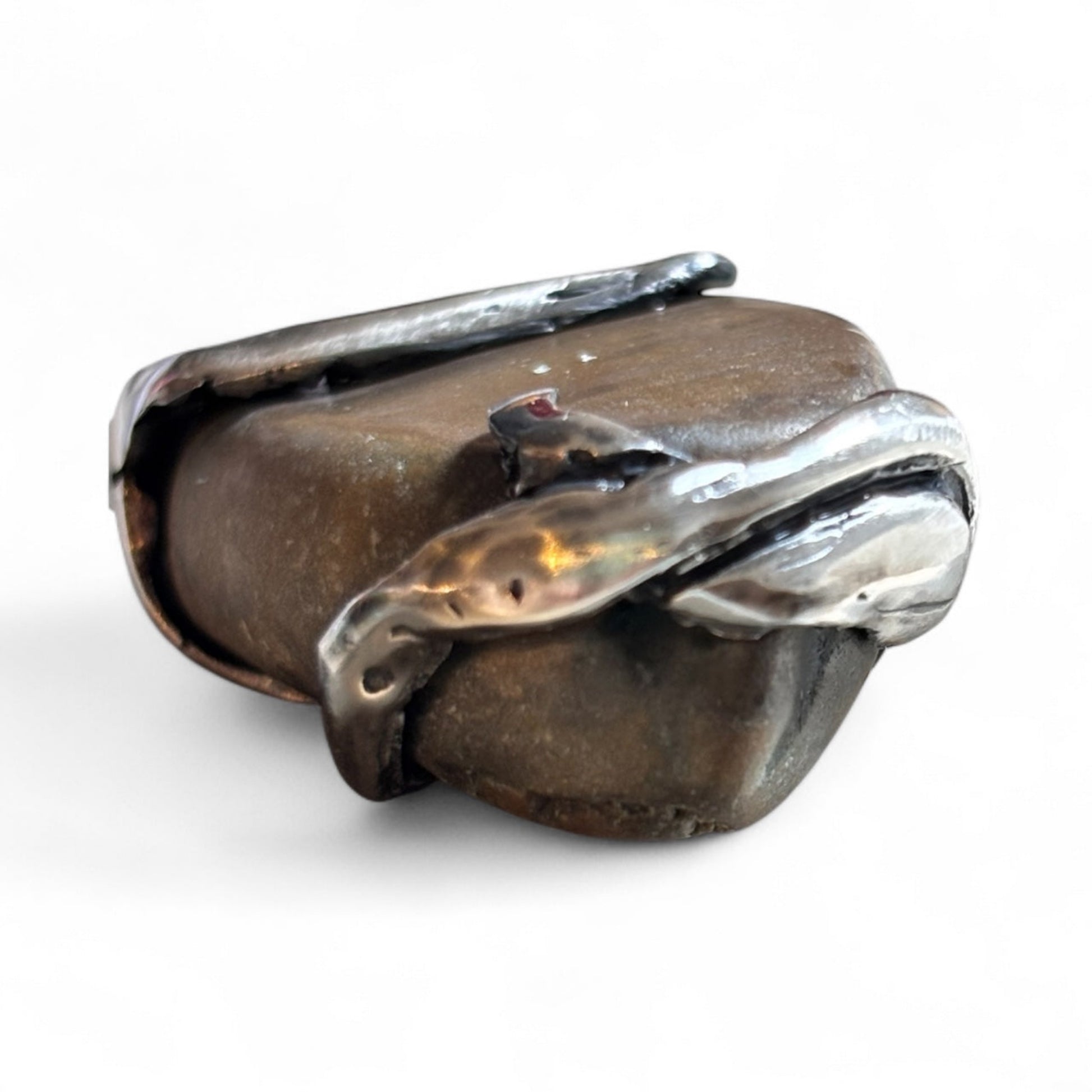 Close-up of a handmade pendant with a raw beach stone encased in an organic silver design.