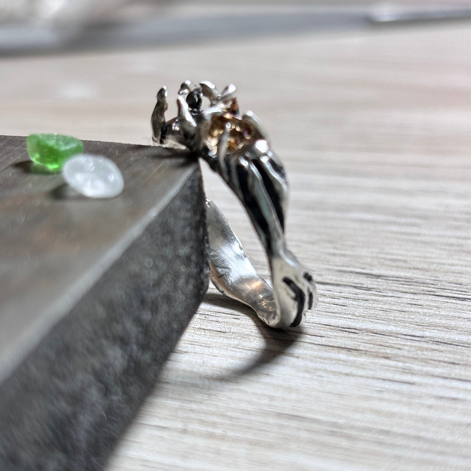 Close-up of a silver ring with a white and green sea glass on a wooden surface