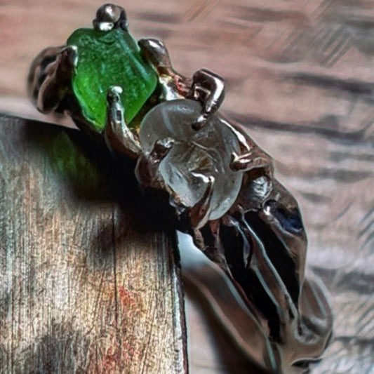 Silver ring with a green and white sea glass gemstone on a wooden surface