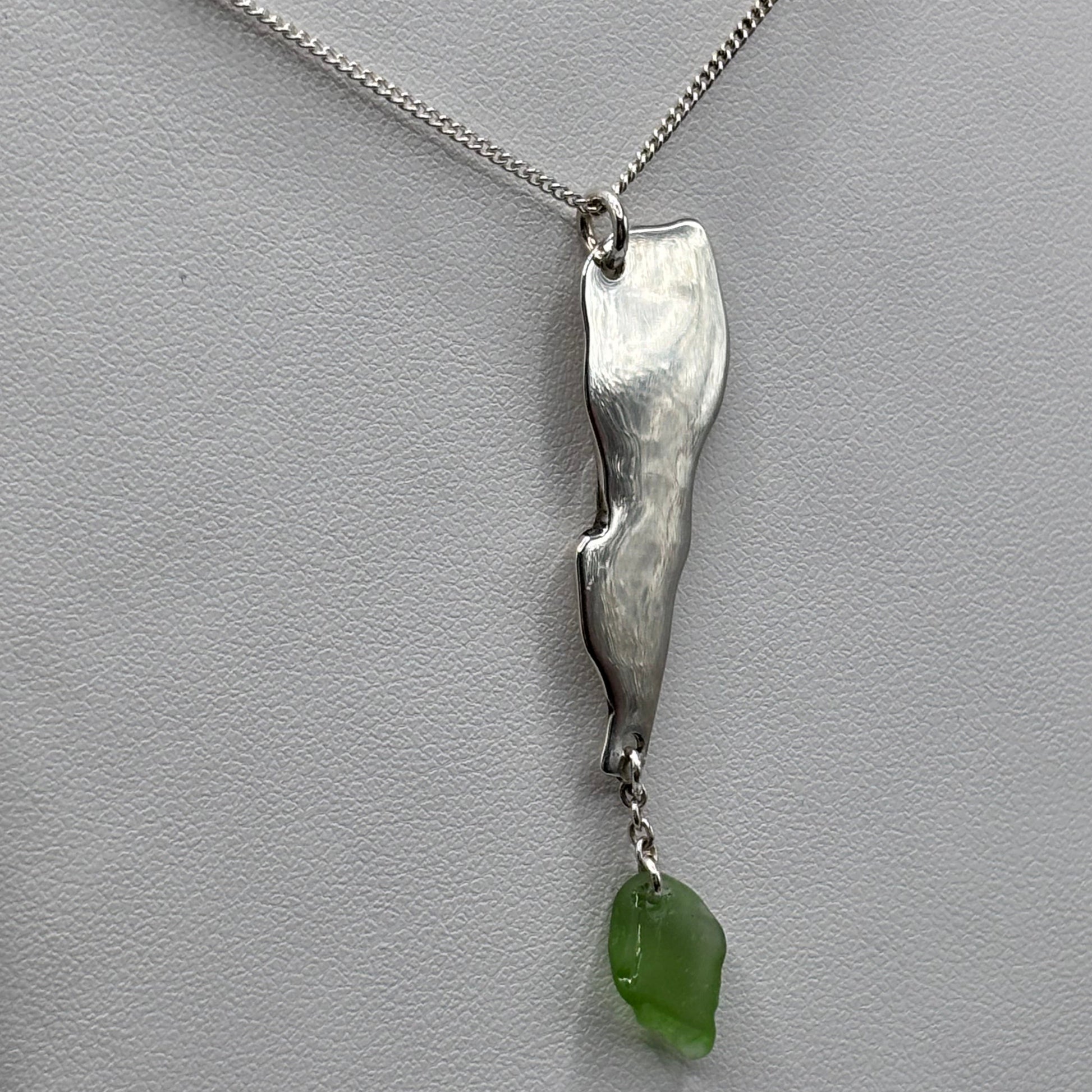Silver necklace with a green pendant on a light gray background