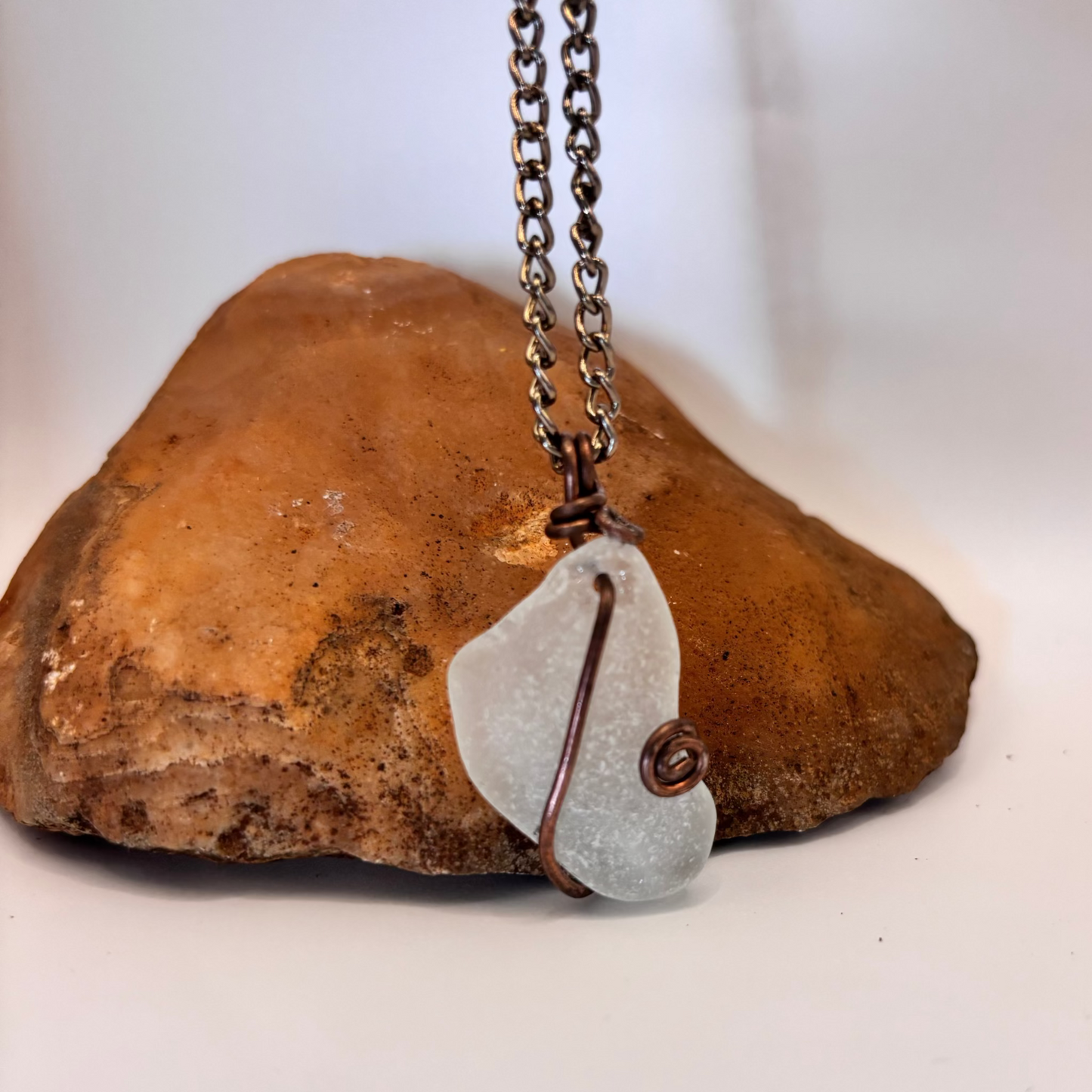 Smooth white sea glass pendant in copper wire on black chain necklace