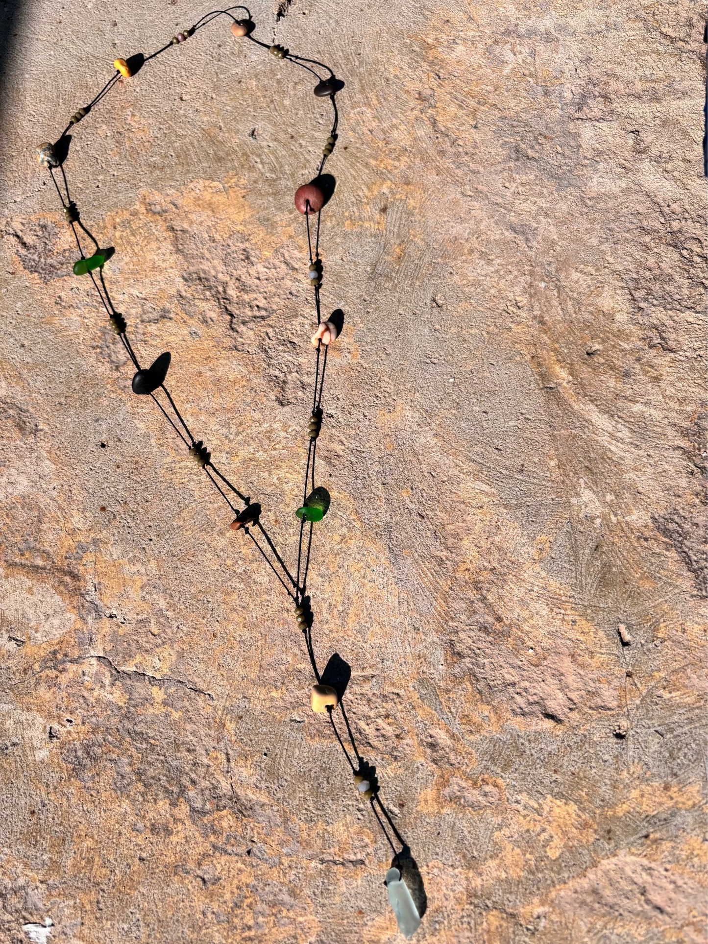 Close-up of a 7ajra necklace made with twelve raw stones, each uniquely shaped and textured.