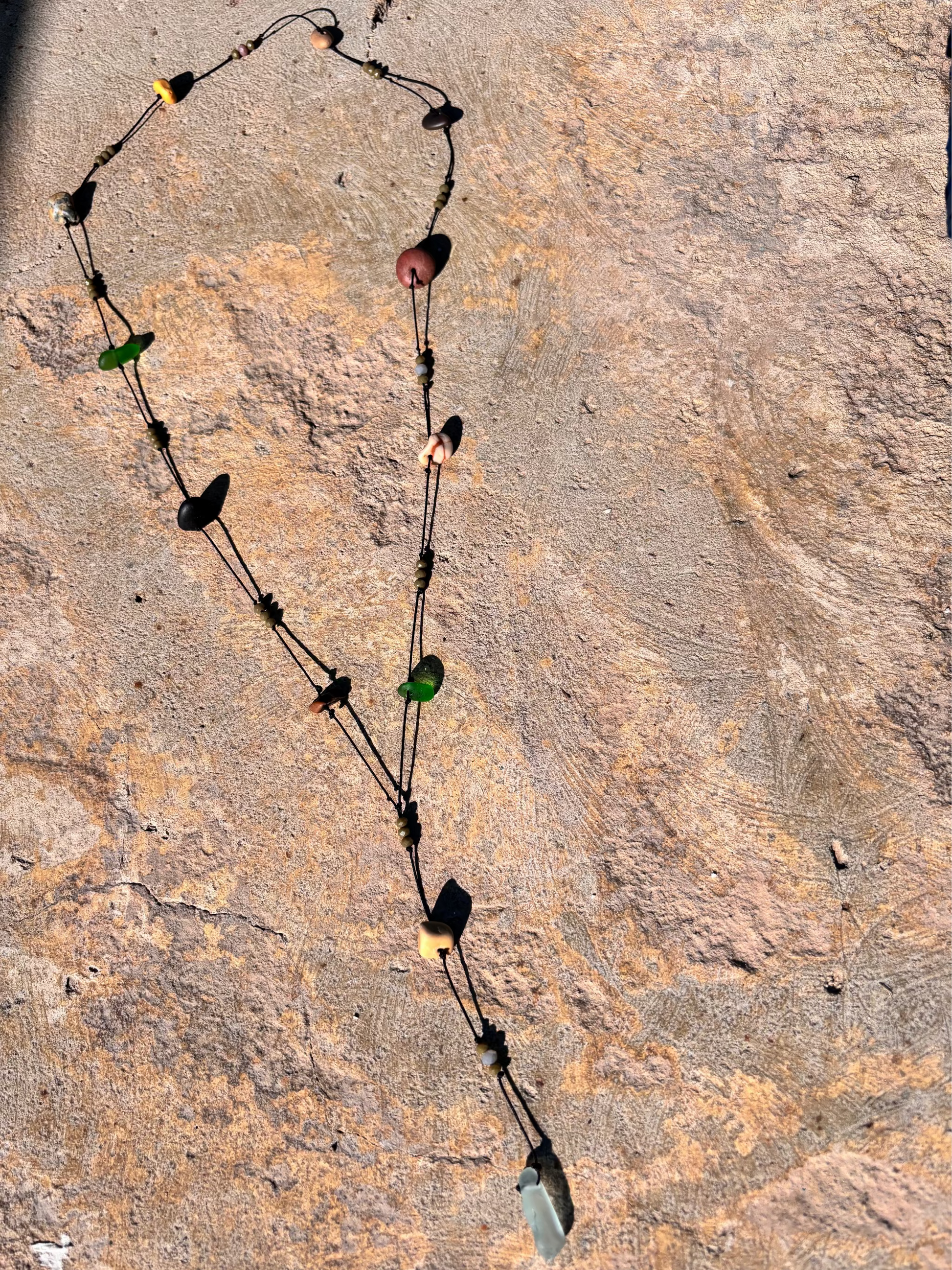 Close-up of a 7ajra necklace made with twelve raw stones, each uniquely shaped and textured.