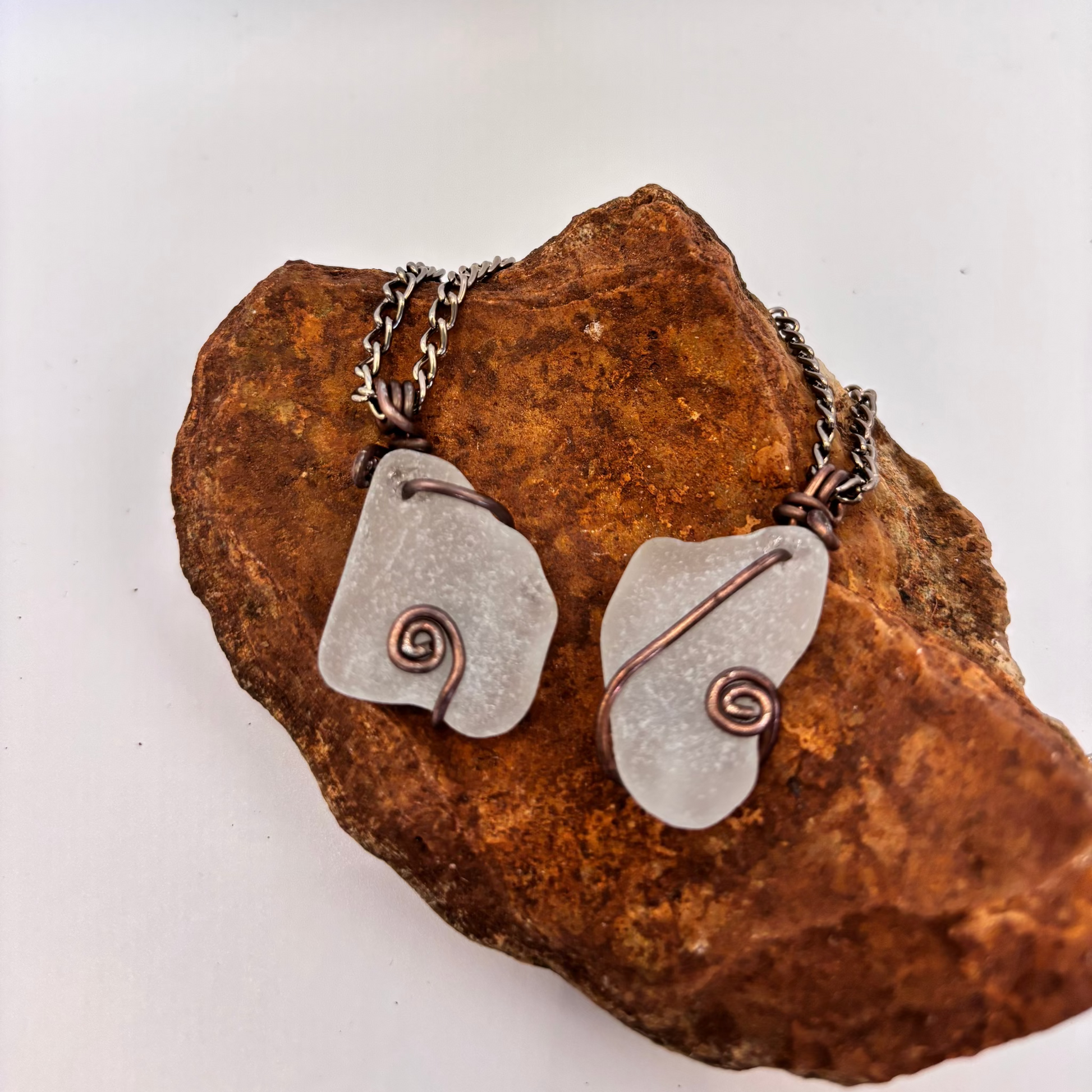 Pair of silver pendants with spiral designs on a textured stone surface
